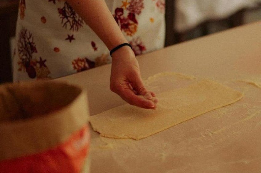 A person rolling out dough on a floured surface. 5