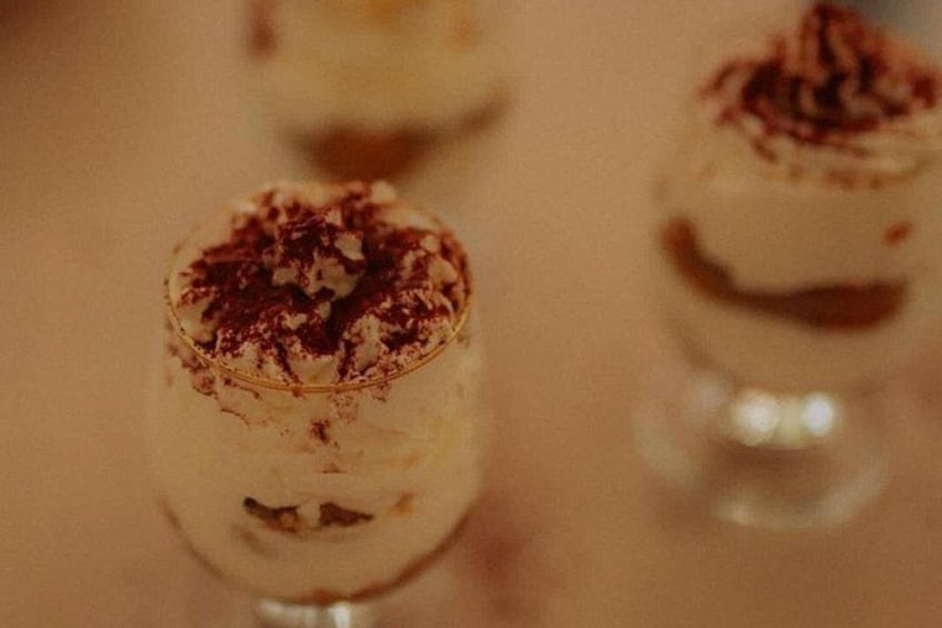 A dessert with a creamy base, topped with a dark sprinkle, possibly cocoa or chocolate. 1