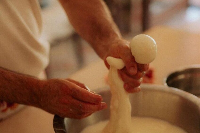 A person kneading dough in a metal bowl. 5