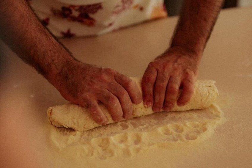 Hands rolling dough on a countertop. 3