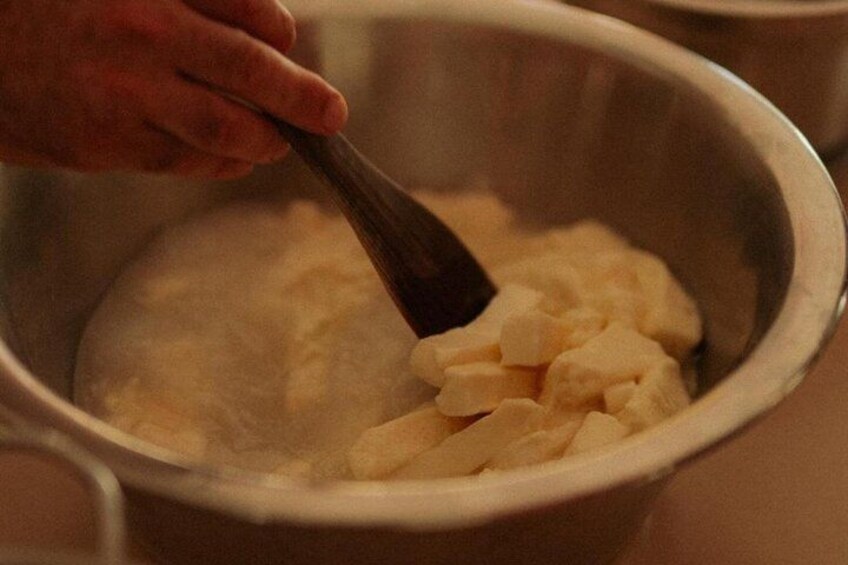 A hand stirring a white substance in a metal bowl. 4