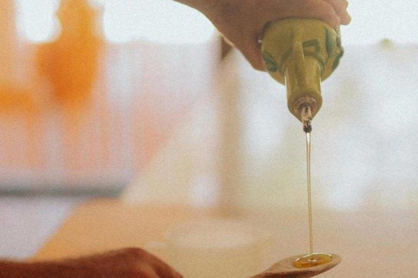 A hand holding a bottle, pouring a clear liquid onto a spoon. 2