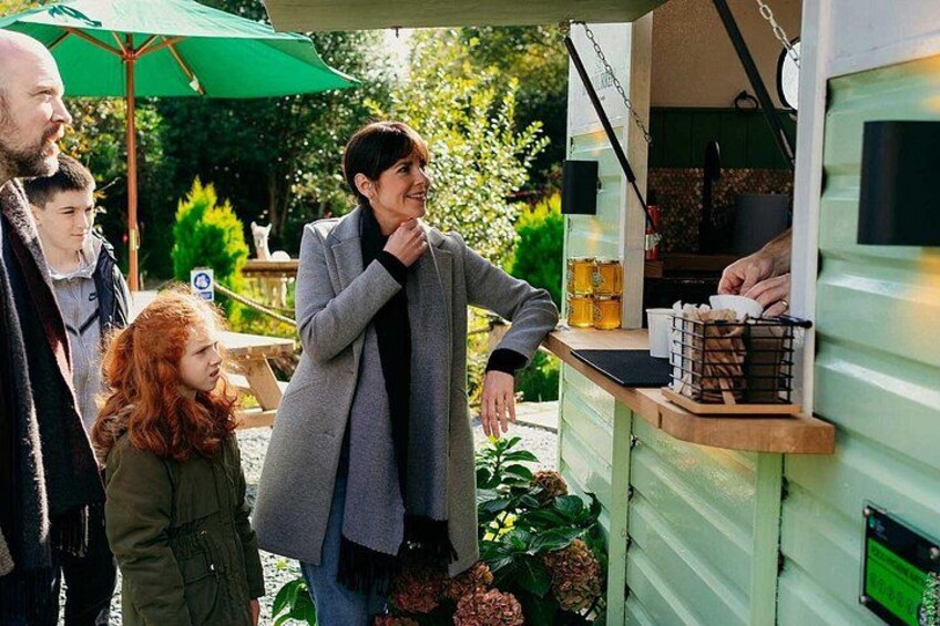 A person standing at a food truck with a green umbrella in the background. 4