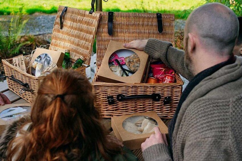 Two wicker baskets with food items and a person holding a box. 2