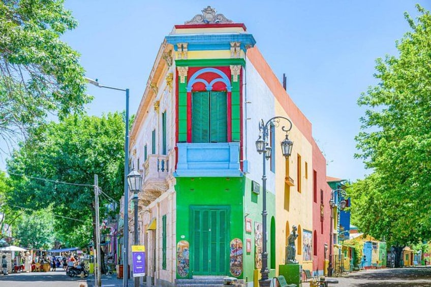 Un edificio colorido con una puerta verde, fachada roja y blanca, y un balcón azul. 2