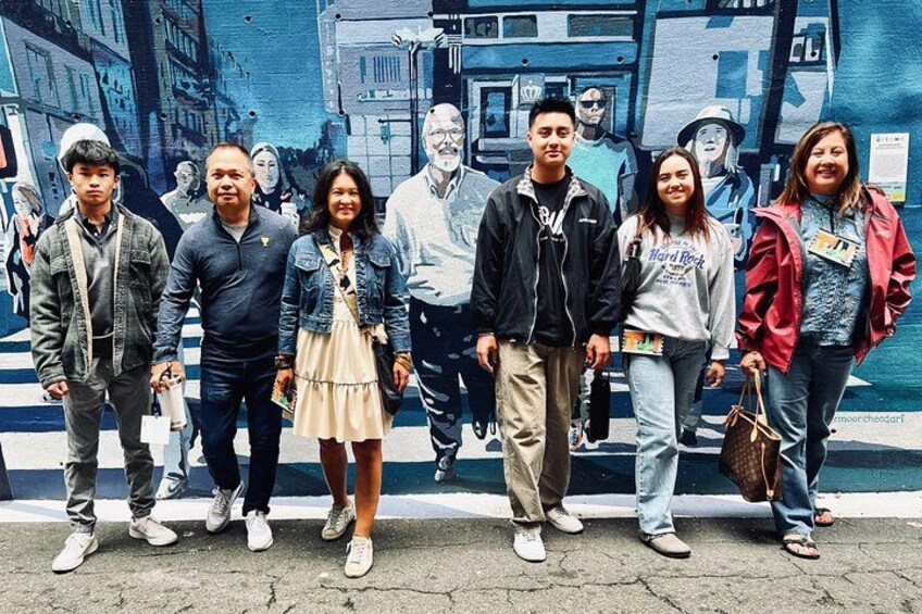 A group of people standing in front of a mural. 2