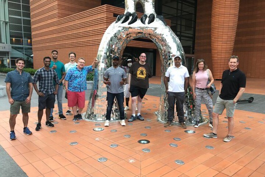 A group of people standing in front of a metallic sculpture. 3