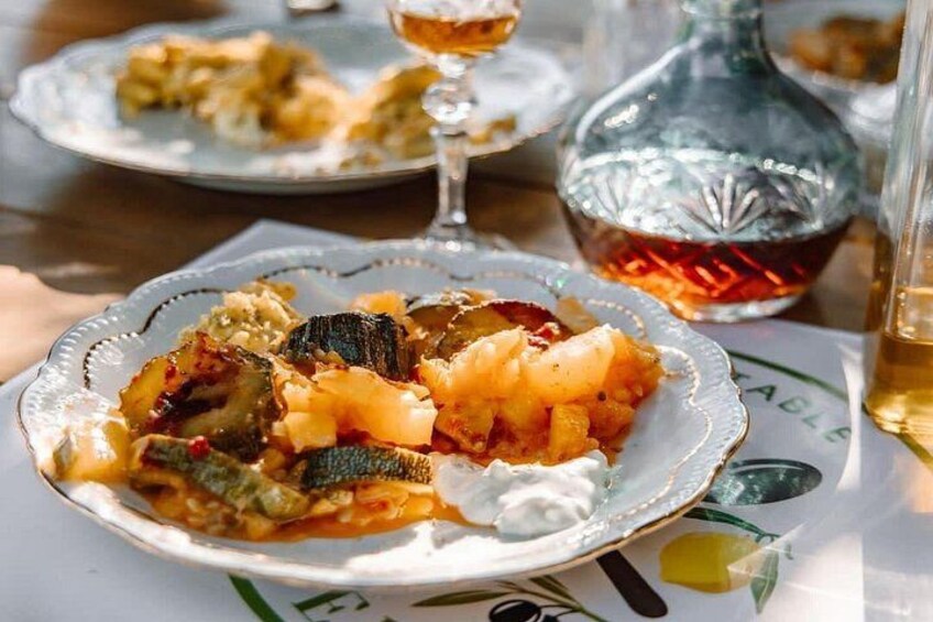 A plate of roasted vegetables with a glass of wine and a bottle in the background. 2