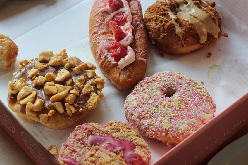 A box of assorted donuts with various toppings. 2