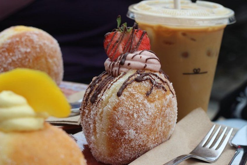 A dessert with a strawberry and chocolate drizzle, a sugar-coated pastry, and a cup of iced coffee with a straw. 3