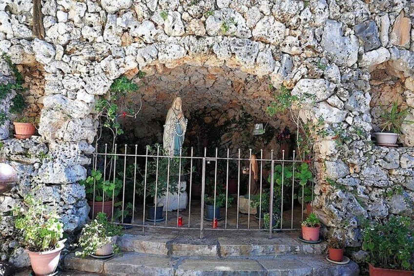 Une arche en pierre ornée de plantes en pot et surmontée d’un portail en métal. 2