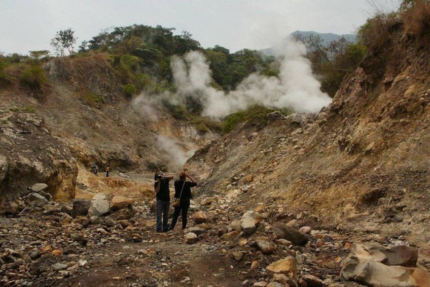 Un paysage rocheux où de la vapeur s’échappe du sol, signe d’une activité géothermique. 3