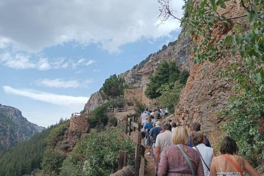 Un groupe de personnes fait de la randonnée sur un sentier rocailleux, entouré de verdure et de montagnes. 3