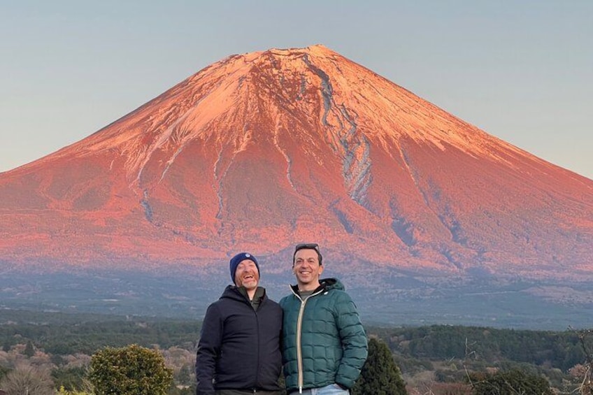 Dos personas frente a un volcán imponente bajo un cielo despejado. 3