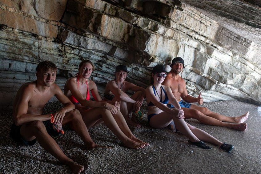 A group of people sitting on a rocky surface in a cave. 3