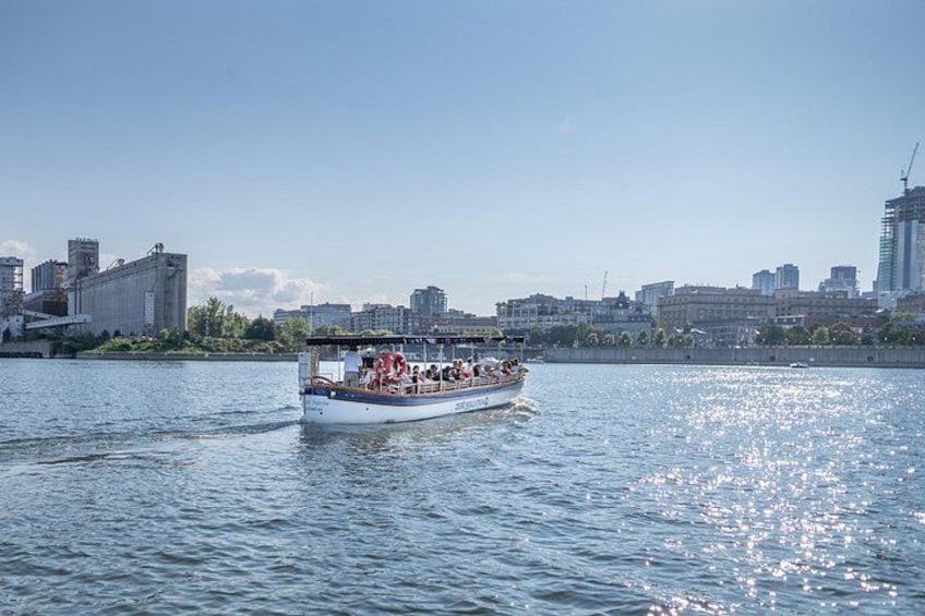 Un bote con pasajeros en un río, con el horizonte de la ciudad al fondo. 3