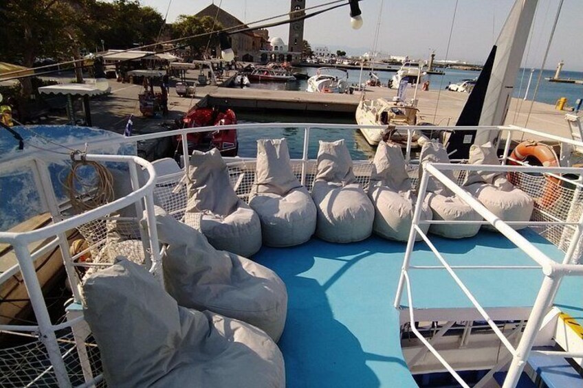 Cubierta de barco con bolsas blancas y piso azul, rodeada de otros barcos y un muelle. 3