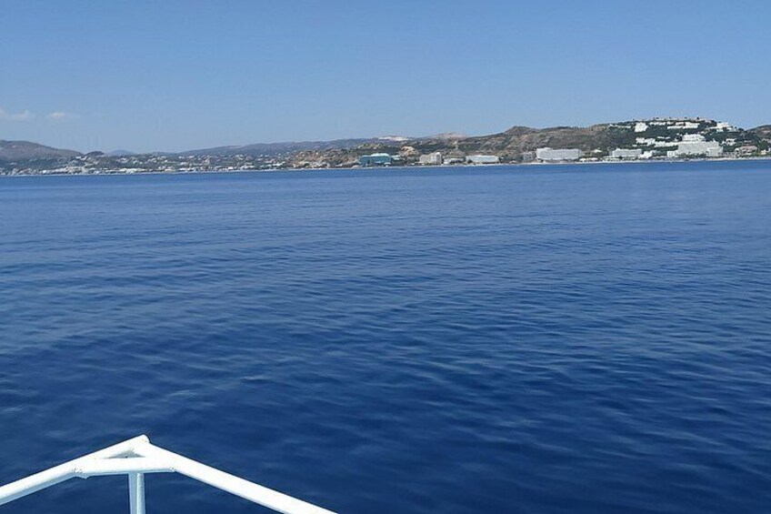 Mar tranquila con un barco en primer plano y un pueblo costero al fondo. 5