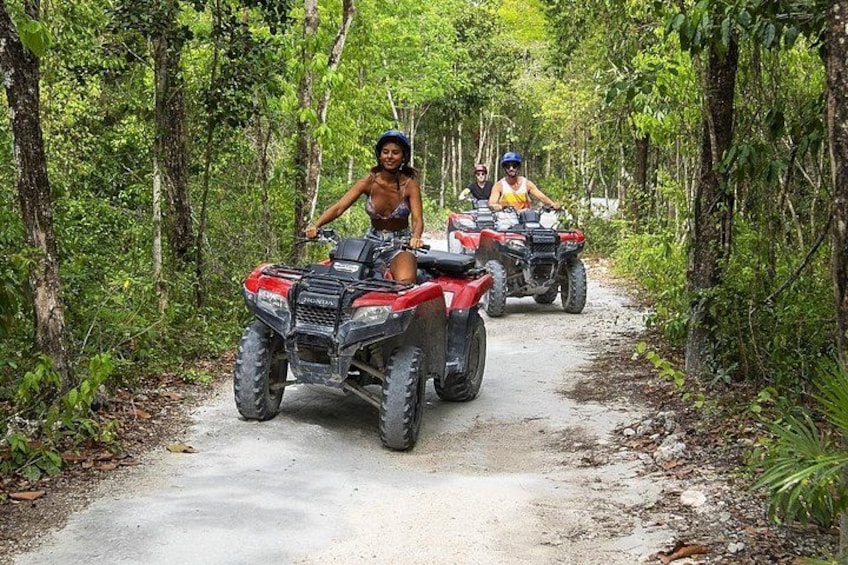 Dos personas cabalgando en cuatrimotos por un sendero de tierra rodeado de bosque denso. 3