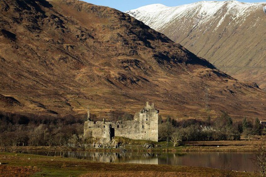 A castle surrounded by a lake and mountains. 5