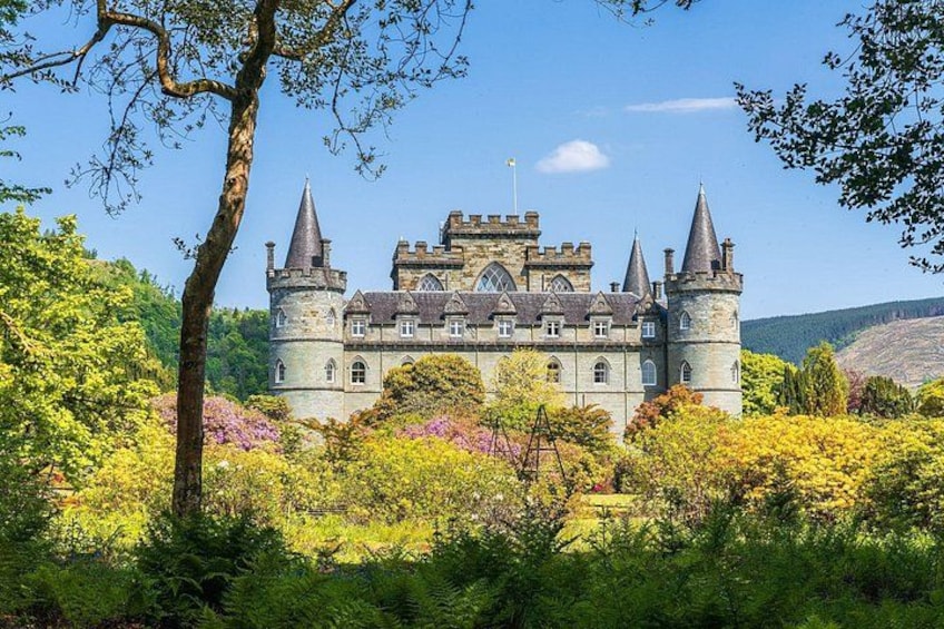 A castle surrounded by lush greenery and vibrant flowers. 1