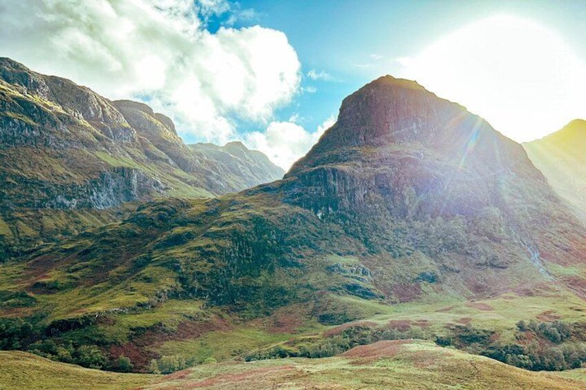 A mountainous landscape with a prominent peak, rolling hills, and a clear sky. 4