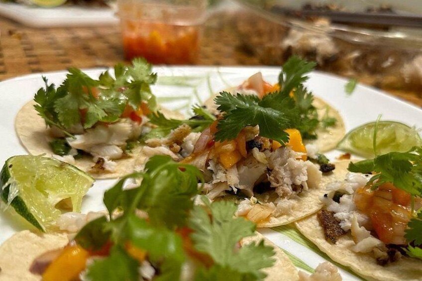 Een bord met taco's, limoenpartjes en een garnering van koriander. 5