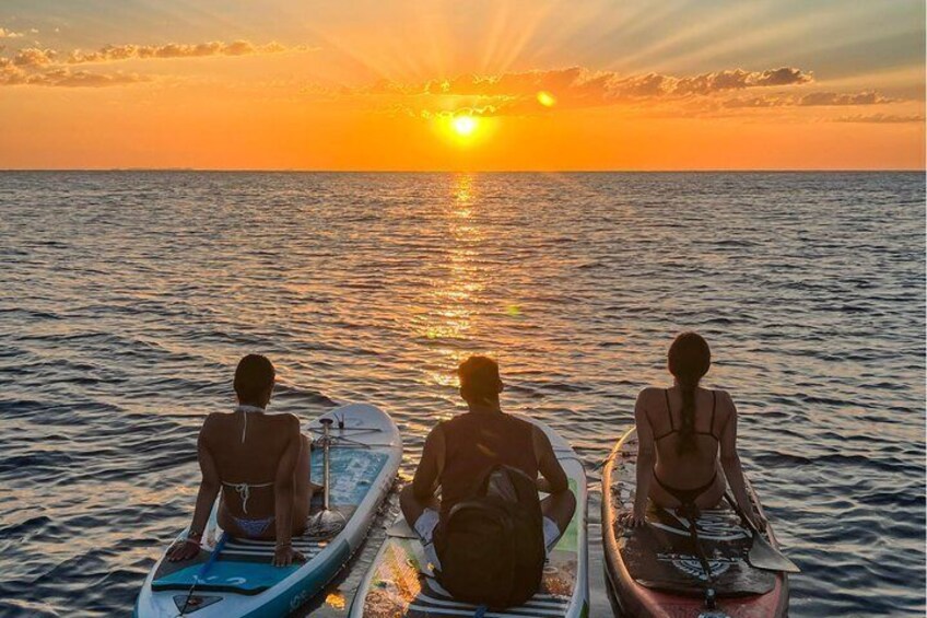Tre persone in kayak su un mare calmo al tramonto. 5
