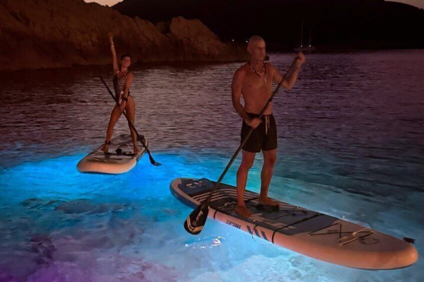 Due persone che fanno paddleboarding su un corpo d'acqua di notte. 4