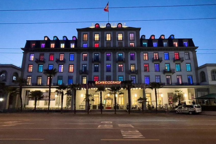 Et hotel med farvede lys i vinduerne, et flag og palmer foran. 3