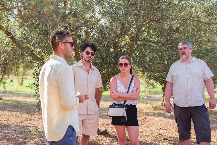 A group of people standing outdoors, possibly in a park or garden, with trees and greenery in the background. 4