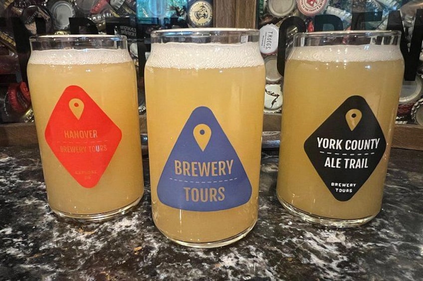 Three beer mugs with brewery tour labels on a bar counter. 2