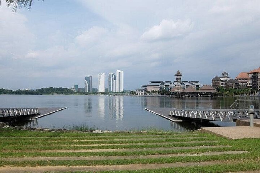 Un lago tranquilo con un puente moderno, edificios al fondo y un espacio verde al frente. 3