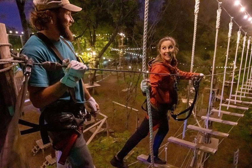 Two people on a rope bridge at night. 4