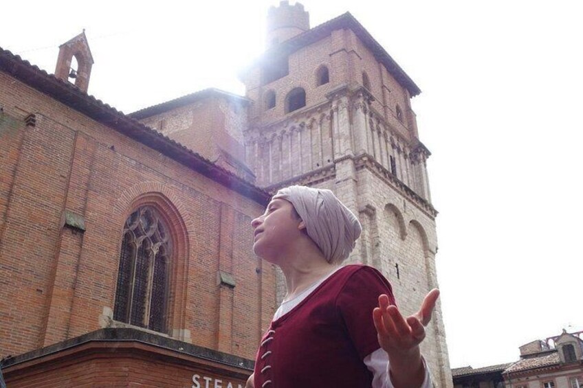 A person in front of a historic church with a bell tower. 2