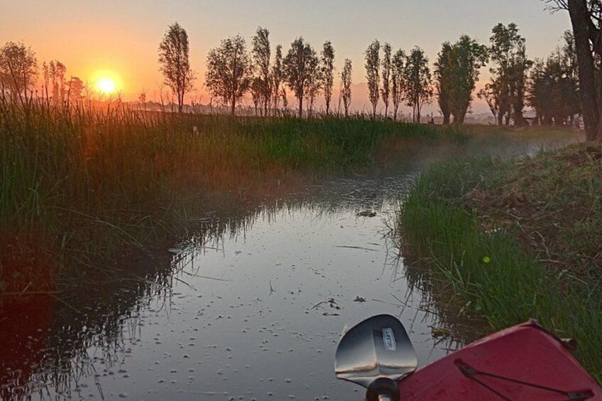 Solnedgang over en rolig flod med en rød båd i forgrunden. 1