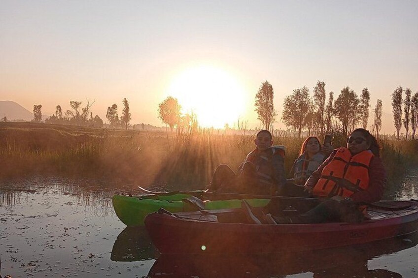En gruppe mennesker i en kano på en stille flod ved solopgang. 3