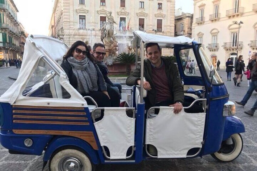 A blue and white three-wheeled vehicle with passengers. 5