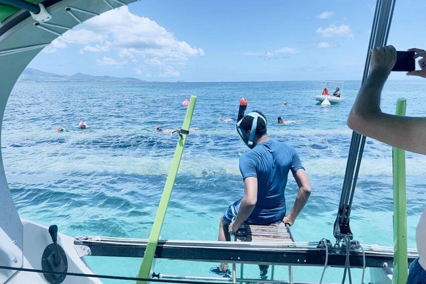 A person on a boat, water sports equipment, and people swimming in the ocean. 4