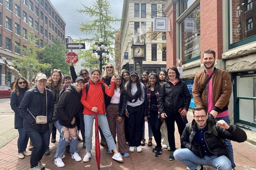 A group of people posing in front of a building with a stop sign and a clock tower. 4