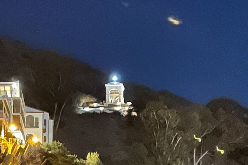 A lit building on a hill with a clear sky. 1