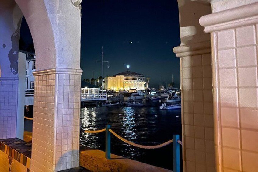 Vista al agua con un edificio iluminado, un muelle con barcos y una barandilla. 3