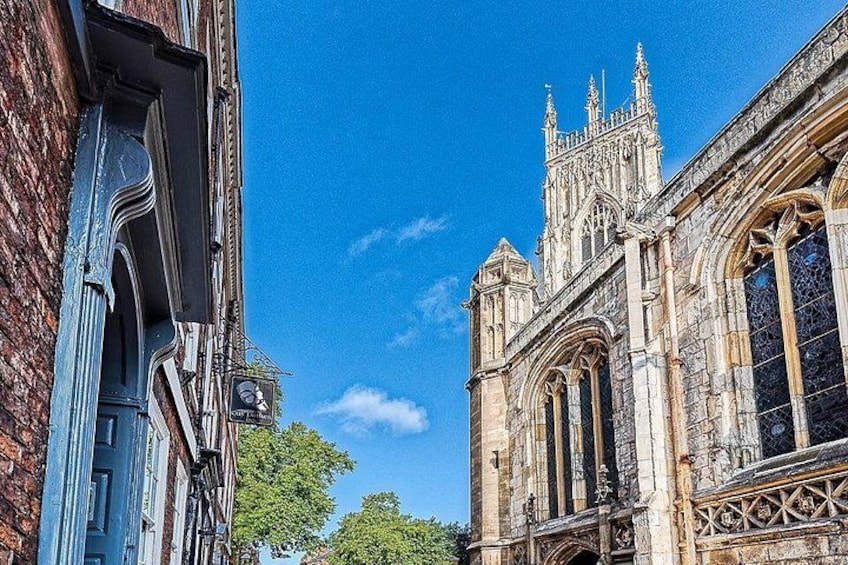 A historic building with Gothic architecture, a clear blue sky, and a tree in the background. 2