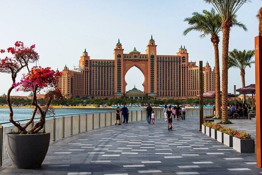 A waterfront promenade with a large hotel and palm trees. 2
