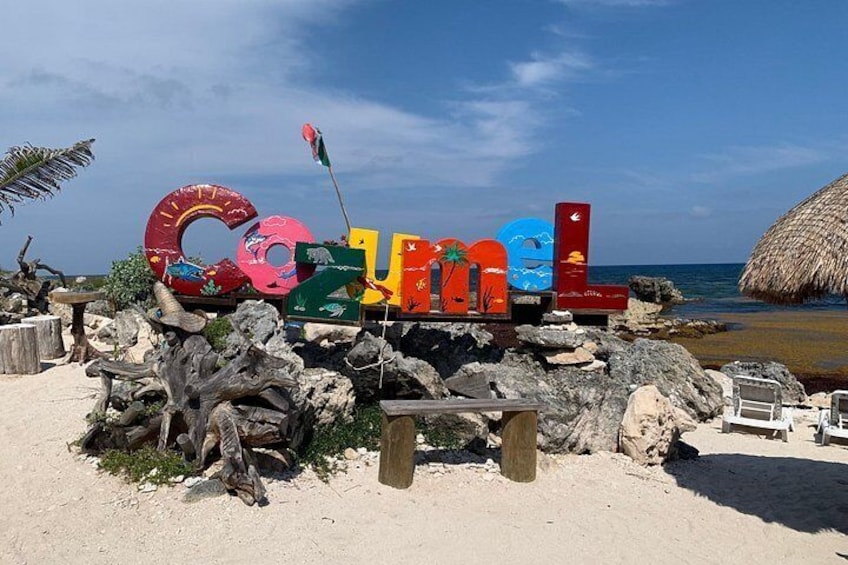 Un panneau coloré placé sur la plage, avec des lettres et des palmiers. 3