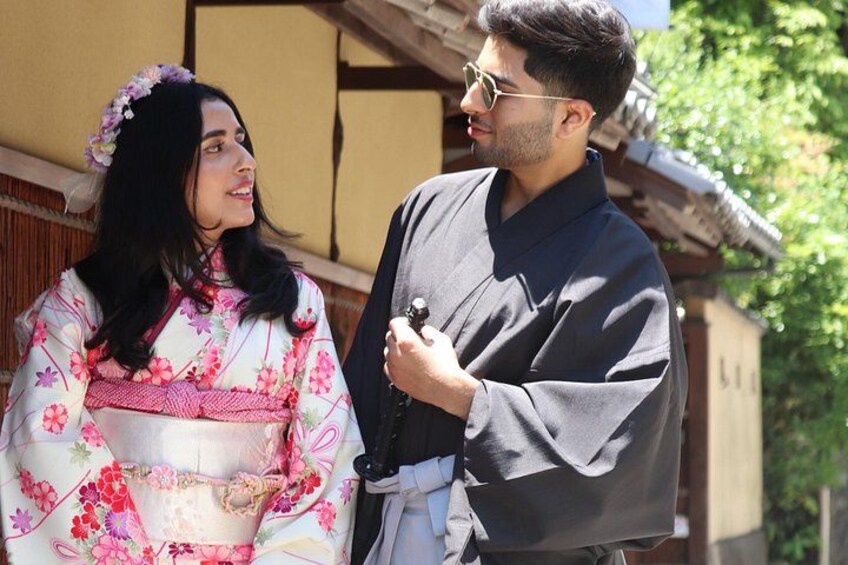 A person in a kimono and another in a dark robe standing in front of a traditional Japanese building. 3