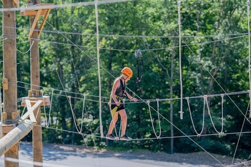 A person on a rope bridge in a wooded area. 3
