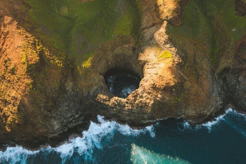 A coastal landscape with a prominent rock formation and a small cave-like opening. 5
