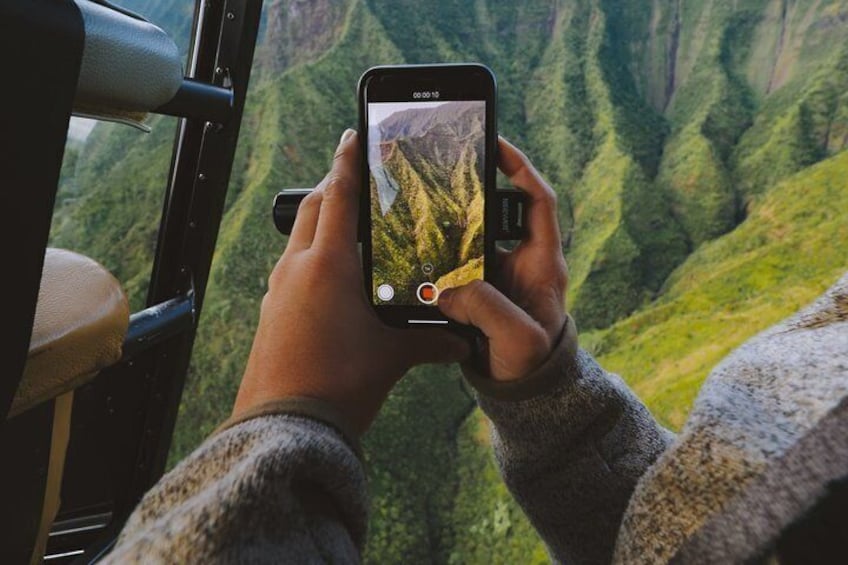 A person holding a smartphone, taking a photo of a mountainous landscape. 3