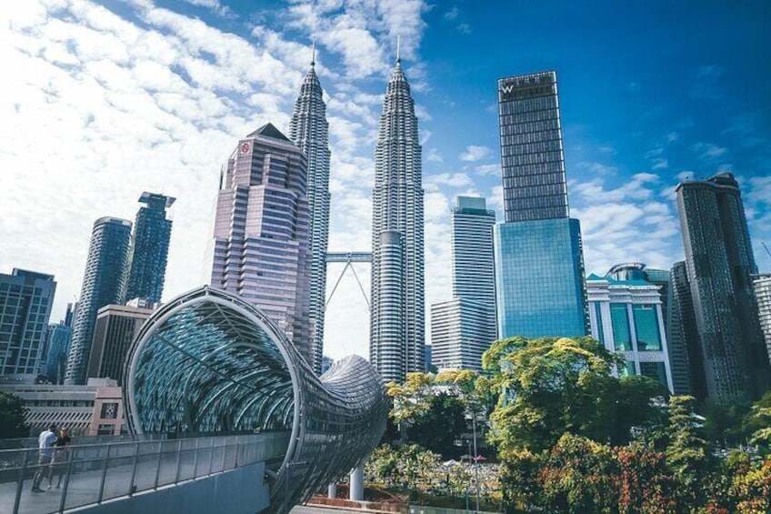 Stadsgezicht met opvallende wolkenkrabbers, waaronder een opvallend gebogen gebouw en de Petronas Towers. 1